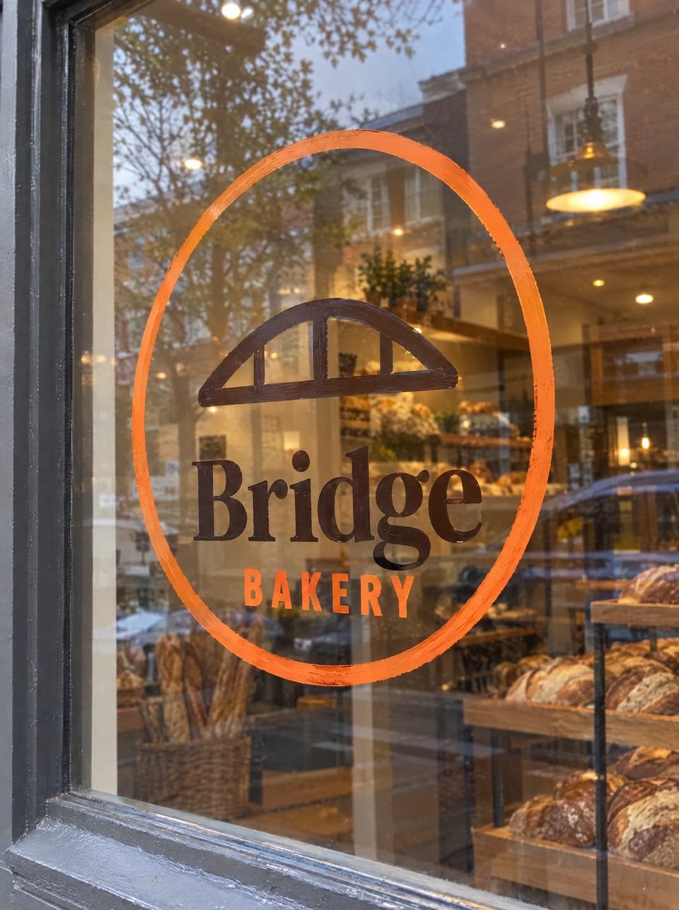 A phone photo of the Bridge Bakery logo painted on a bakery window